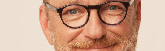 Homme souriant portant des lunettes rondes noires – monture élégante pour homme senior signée Lunettes Pour Tous